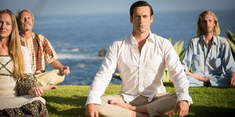 Don Draper sitting on the ground cross legged, meditating with others in Mad Men.