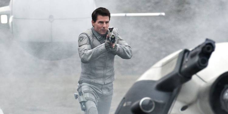 Tom Cruise aiming a futuristic rifle in a white futuristic uniform in Oblivion.