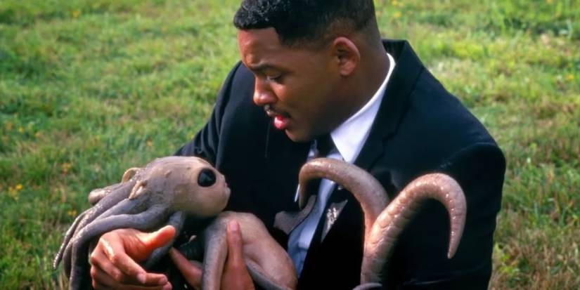 Agent J holding a baby octopus-like alien in Men in Black
