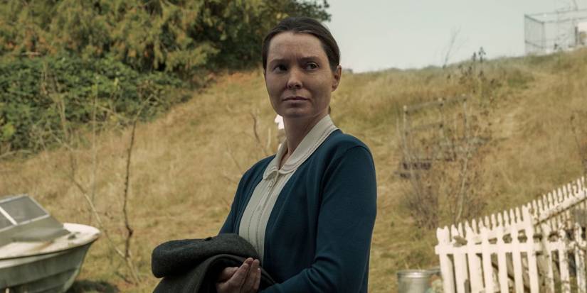 Samantha Sloyan as Bev holding a coat and looking to the side with a serious expression in 'Midnight Mass'.