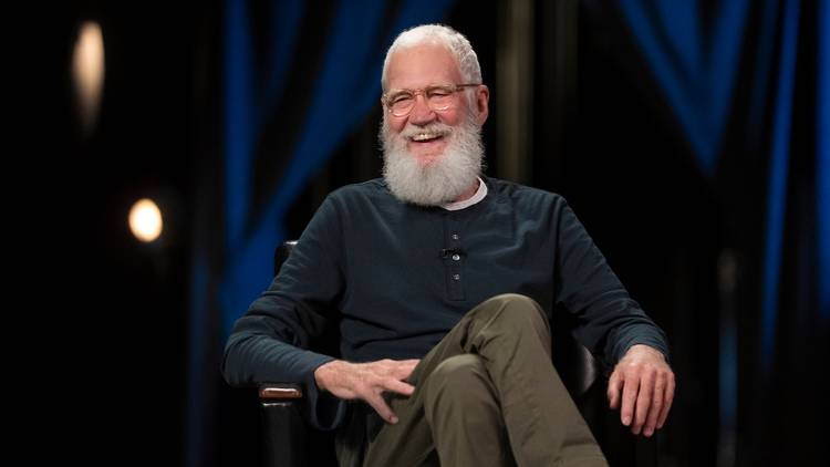 David Letterman sitting in a chair laughing