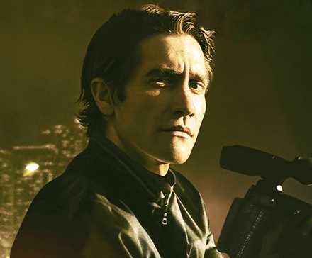 Jake Gyllenhaal holding a camera and looking to his right in Nightcrawler.