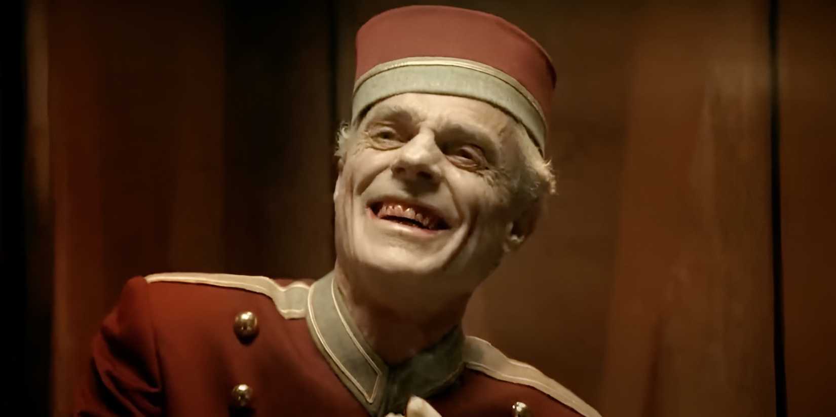 A man in a hotel doorman uniform laughs manically in Nightmares & Dreamscapes.