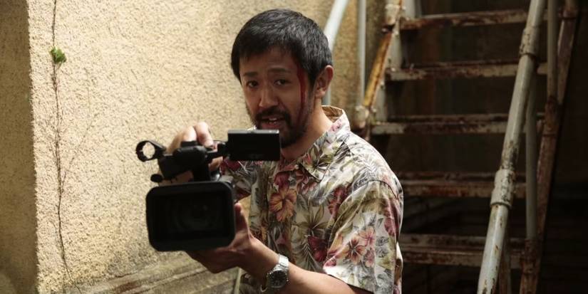 An injured man holds up a film camera in One Cut of the Dead.
