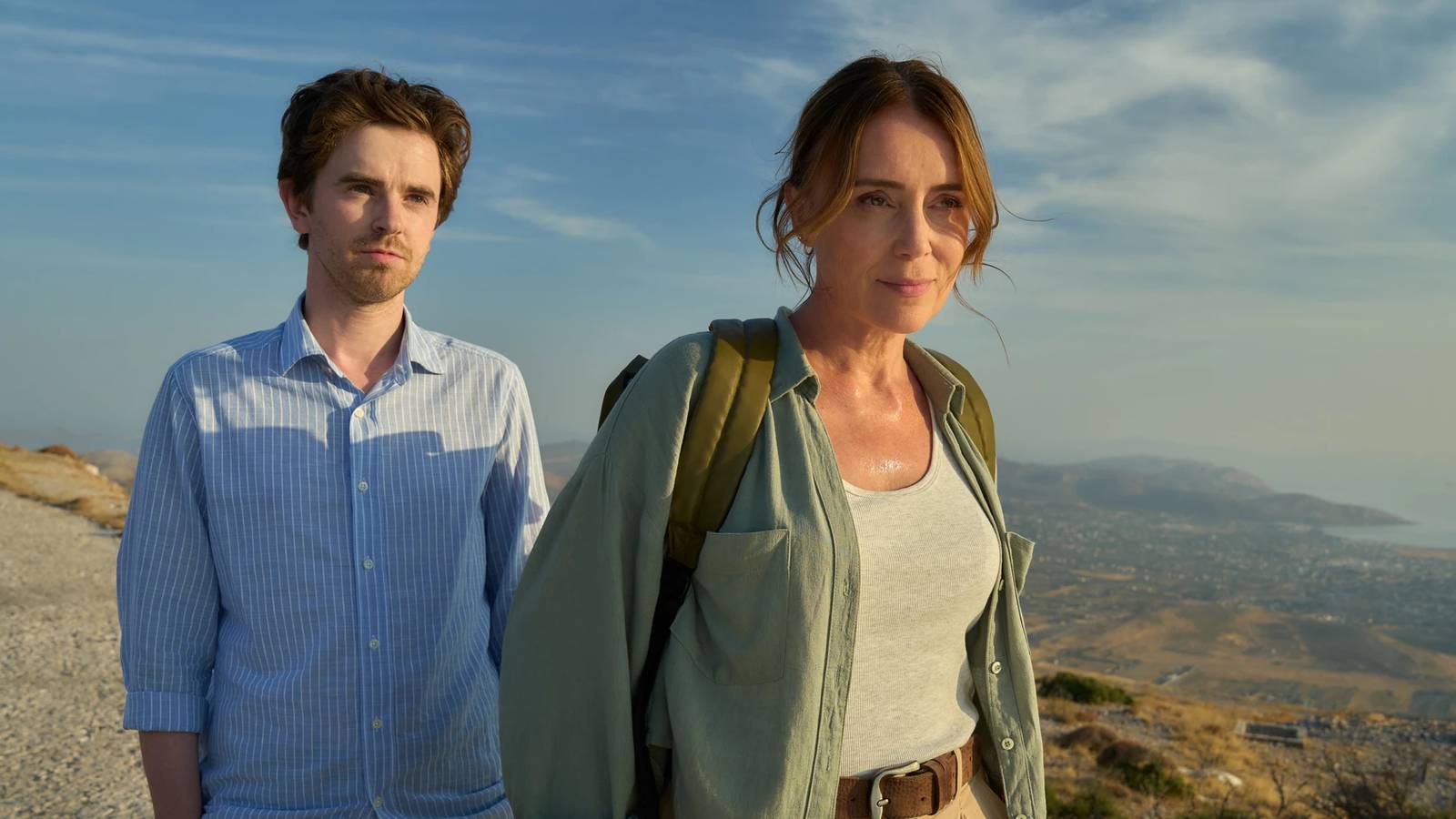 Keeley Hawes and Freddie Highmore stood atop a hill and looking into the distance in The Assassin