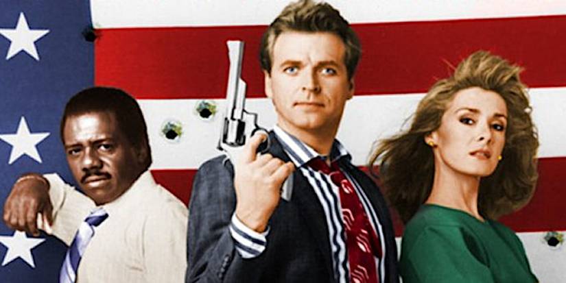 The cast of Sledge Hammer! stand in front of an American Flag with bullet holes in it.