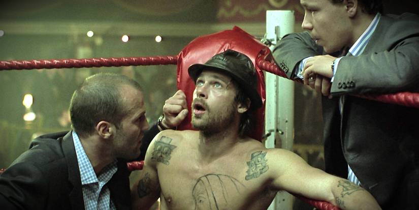 Brad Pitt as Mickey O'Neil in the corner of a boxing ring looking dazed as Jason Statham as Turkish talks to him in 'Snatch' (2000).