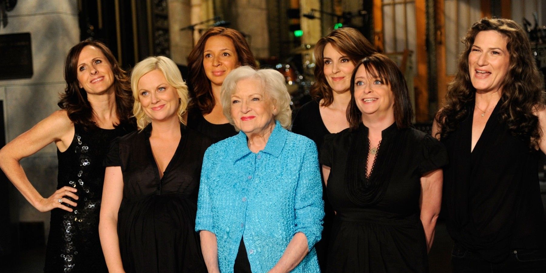 Female SNL cast members around Betty White during her opening monologue