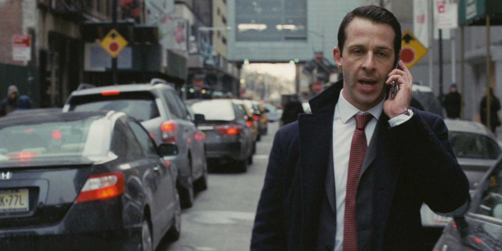 A man walks down a busy city street while talking on the phone in Succession episode Which Side Are You On.