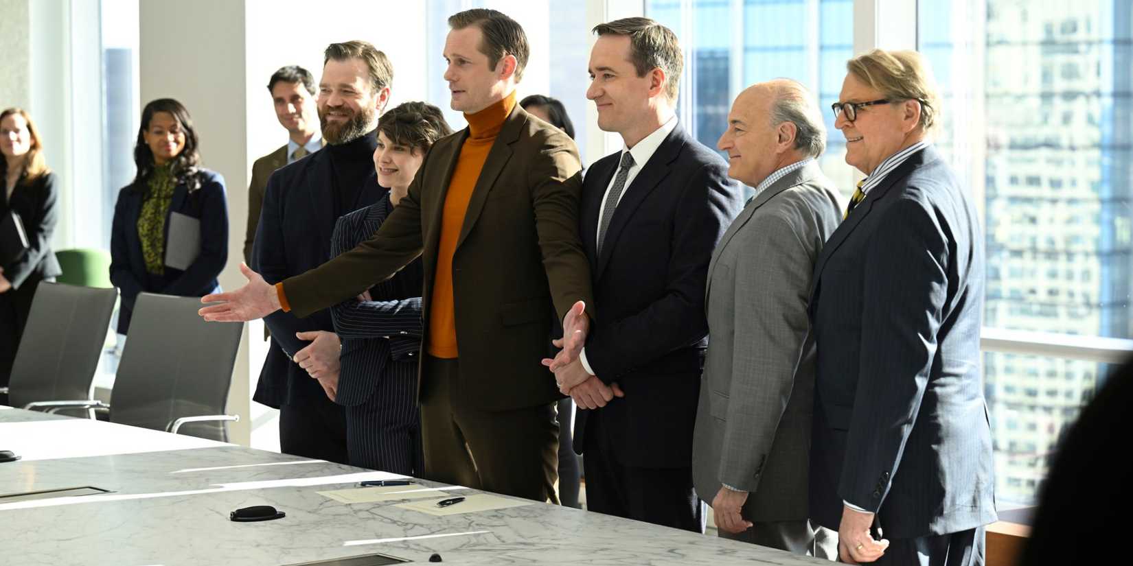 The cast smiling at a long conference room table in Succession episode With Open Eyes.