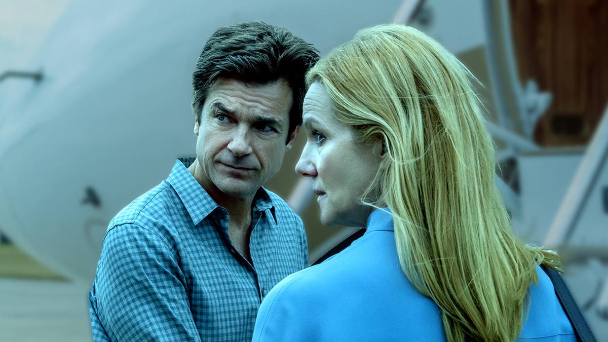 A man and woman look behind them with serious expressions in Ozark.