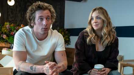 Abby Elliott as Sugar sitting in the empty restaurant next to Jeremy Allen White as Carmy in The Bear Season 2.