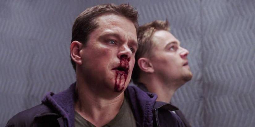 Matt Damon with a bloody nose stands next to Leonardo DiCaprio in an elevator