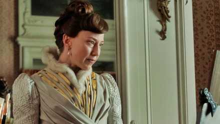 Carrie Coon looking at a portrait in progress in The Gilded Age.