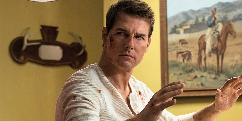 Tom Cruise as Jack Reacher with his hands raised in Jack Reacher: Never Go Back