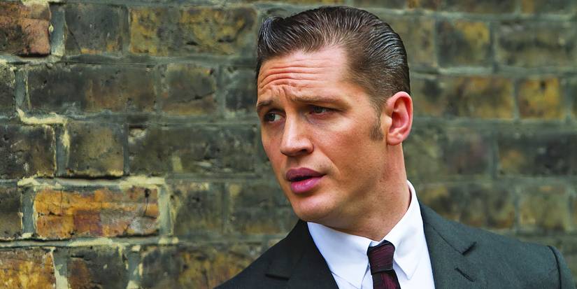 Tom Hardy with slicked hair against a brick wall in Legend