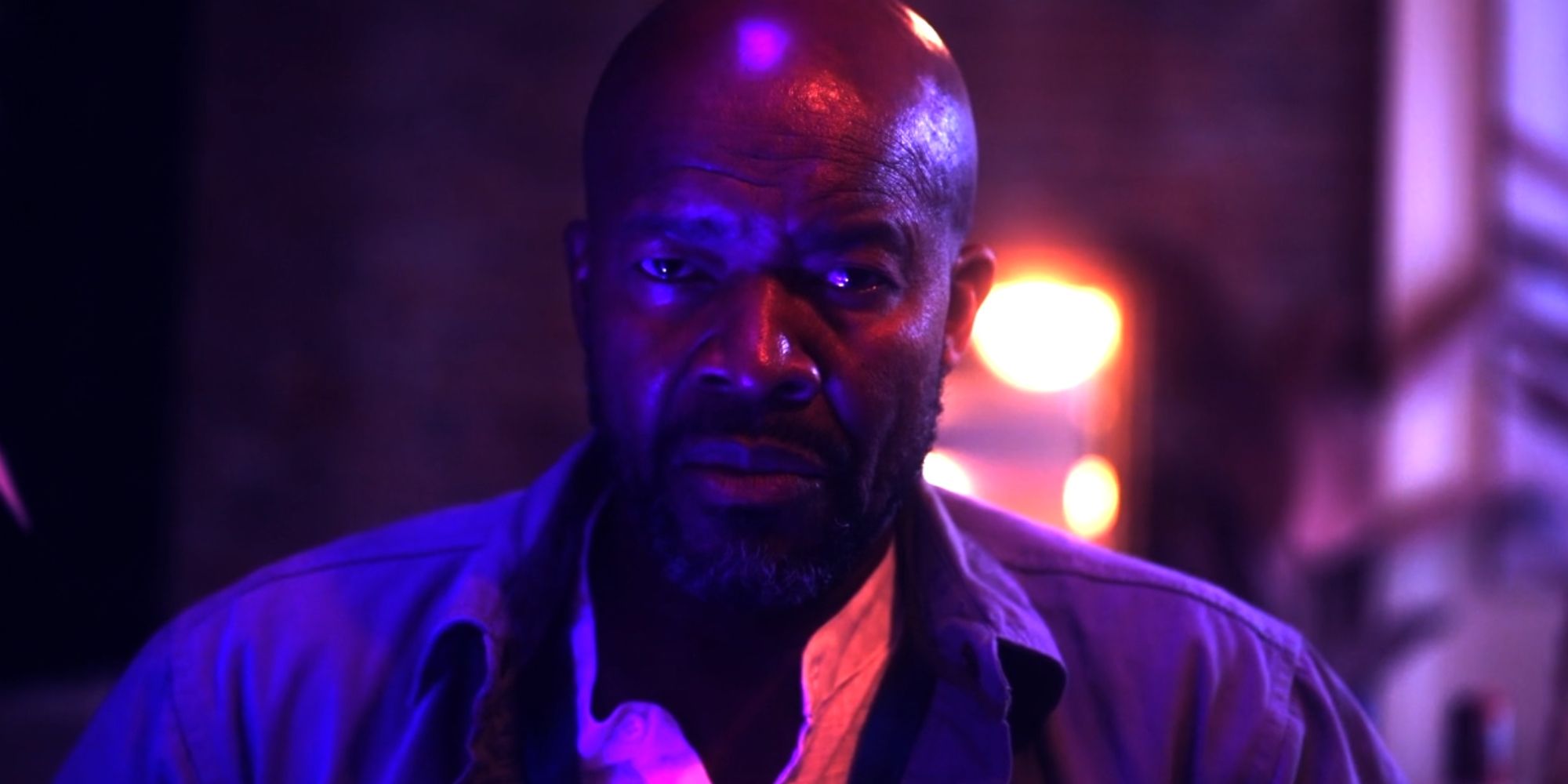 Leon Addison Brown as Steven, bathed in neon light and looking straight into the camera in Atrabilious.