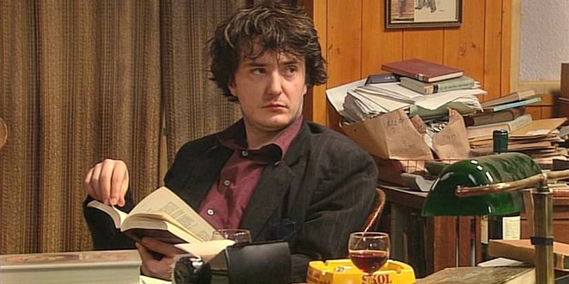 Dylan Moran dans le rôle de Bernard Black lisant un livre et ayant l'air misérable dans Black Books (2000-2004)