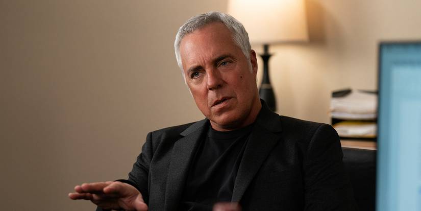 Harry Bosch sitting in a chair talking with his hand out in Bosch.