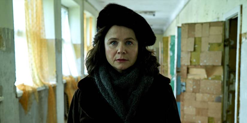 Emily Watson faces the camera and walks down an empty hallway in Chernobyl.