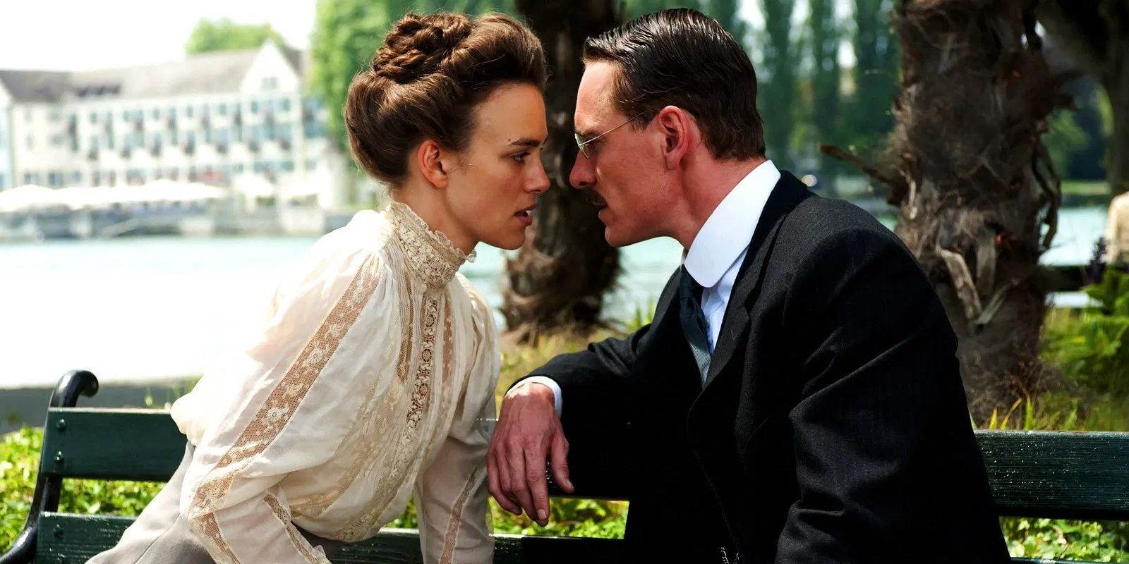 Keira Knightley and Michael Fassbender as Sabina and Carl Jung, sat on a park bench looking directly at each other in A Dangerous Method.