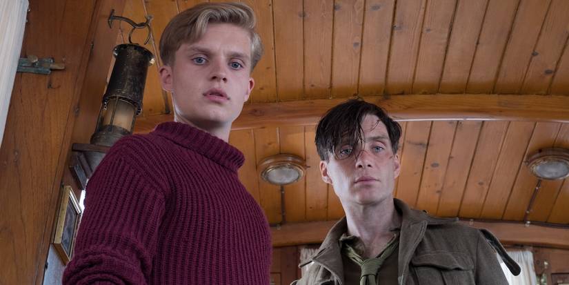Cillian Murphy and Tom Glynn-Carney look down at something while on a small boat in Dunkirk