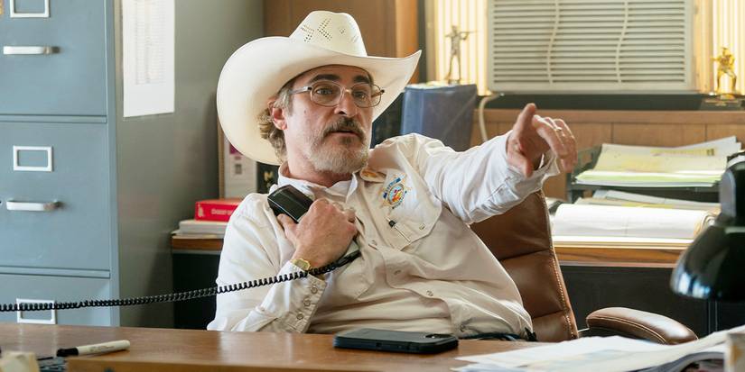 Sheriff Joe Cross sitting at his desk with a phone pointing in Eddington