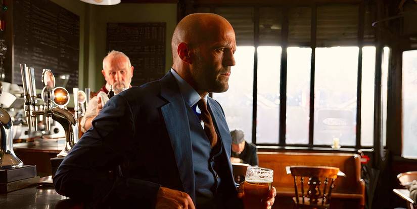 Jason Statham leans against a bar in Hobbs and Shaw