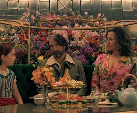 Sophie Sloan, Mads Mikkelsen, and Sigourney Weaver wear bright costumes and chat around a table
