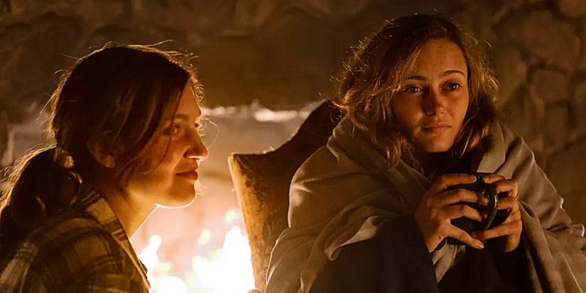 Shauna Shipman and Jackie Taylor sit in front of a fire and smile in Jackie's death dream in Yellowjackets.
