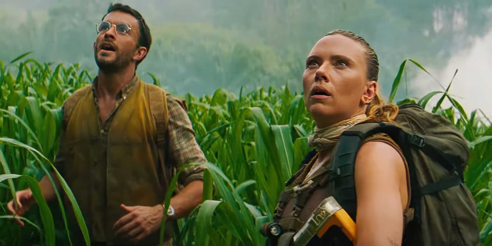 Scarlett Johansson and Jonathan Bailey look up in wonder from the tall grass in Jurassic World Rebirth