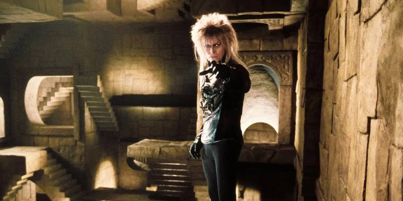 David Bowie as Jareth in a room of M.C. Escher-style staircases pointing at the camera in Labyrinth.