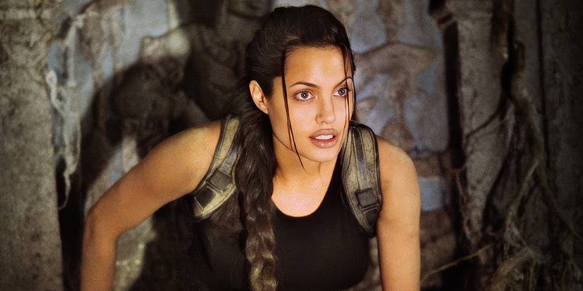 Lara Croft stands with a confident look in a hazy tomb