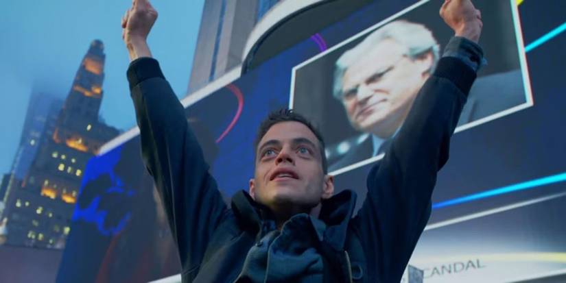 Elliot raising his arms with a billboard behind him in Mr. Robot.