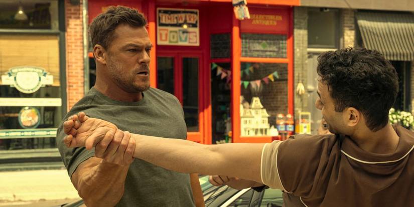 Alan Ritchson as Jack Reacher grabbing a man's arm, midswing, in Season 3.