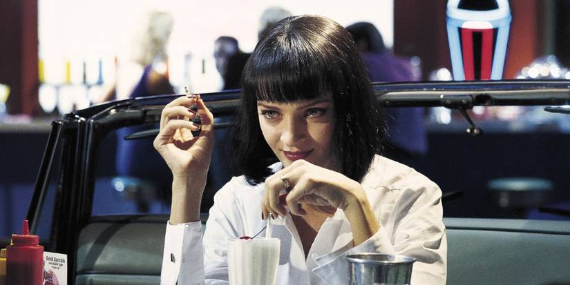 Uma Thurman As Mia Wallace mengenakan atasan putih merokok sebatang rokok di 'Pulp Fiction'