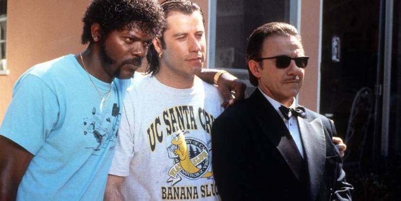 Samuel L. Jackson, John Travolta and Harvey Keitel as Jules Winnfield, Vincent Vega, and Mr. Wolf wearing t shirts and a black suit smiling in 'Pulp Fiction'