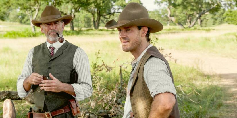 Pierce Brosnan and Henry Garrett as Eli and Pete smoking a pipe and wearing cowboy hats standing outside in 'The Son.'
