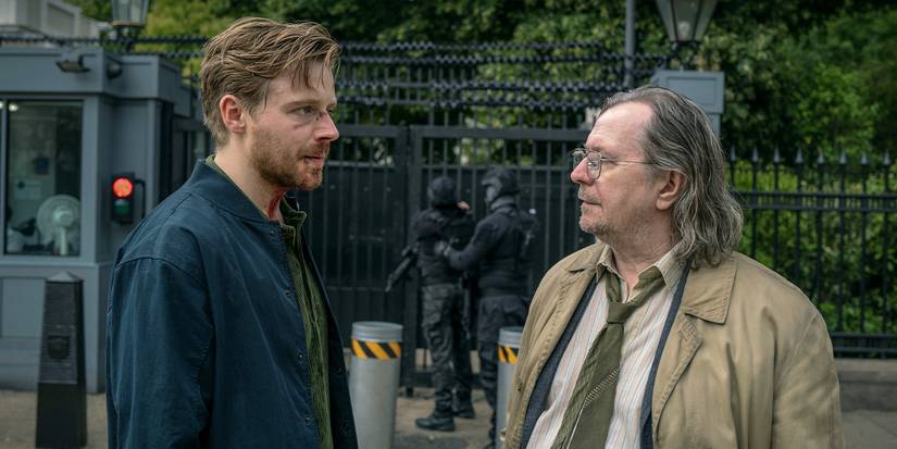 Jack Lowden and Gary Oldman talking outside on a city sidewalk in Slow Horses.