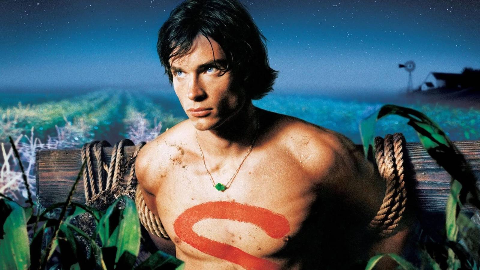 Tom Welling tied to a post in a cornfield with the letter 