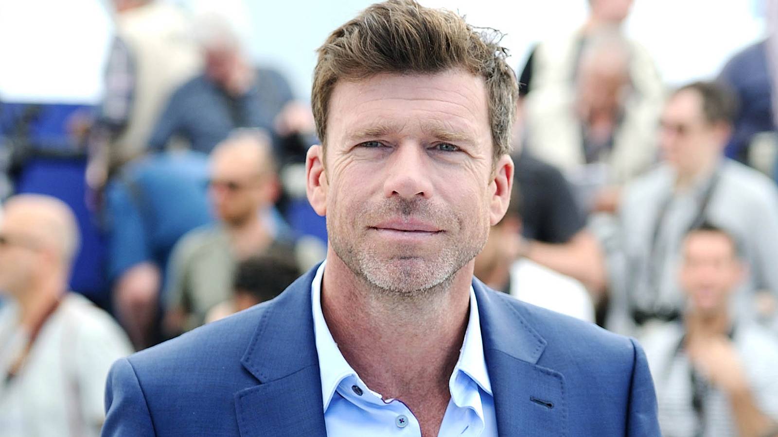 Taylor Sheridan smiling in a suit on the Red Carpet