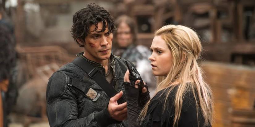 Clarke Griffin (Eliza Taylor) with a walkie-talkie as Bellamy Blake (Bob Morley) stands near in The 100.