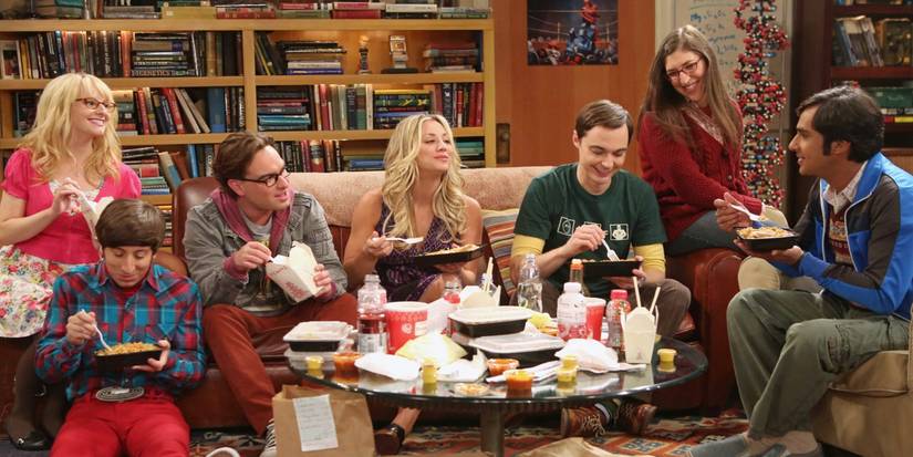 The cast eating food and smiling on the couch in The Big Bang Theory.