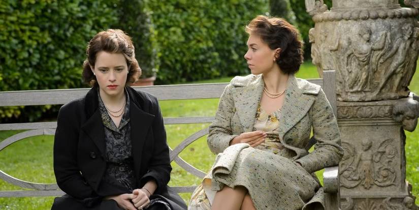 Vanessa Kirby as Princess Margaret and Claire Foy as Queen Elizabeth II seated together on a bench in a still from 'The Crown.'