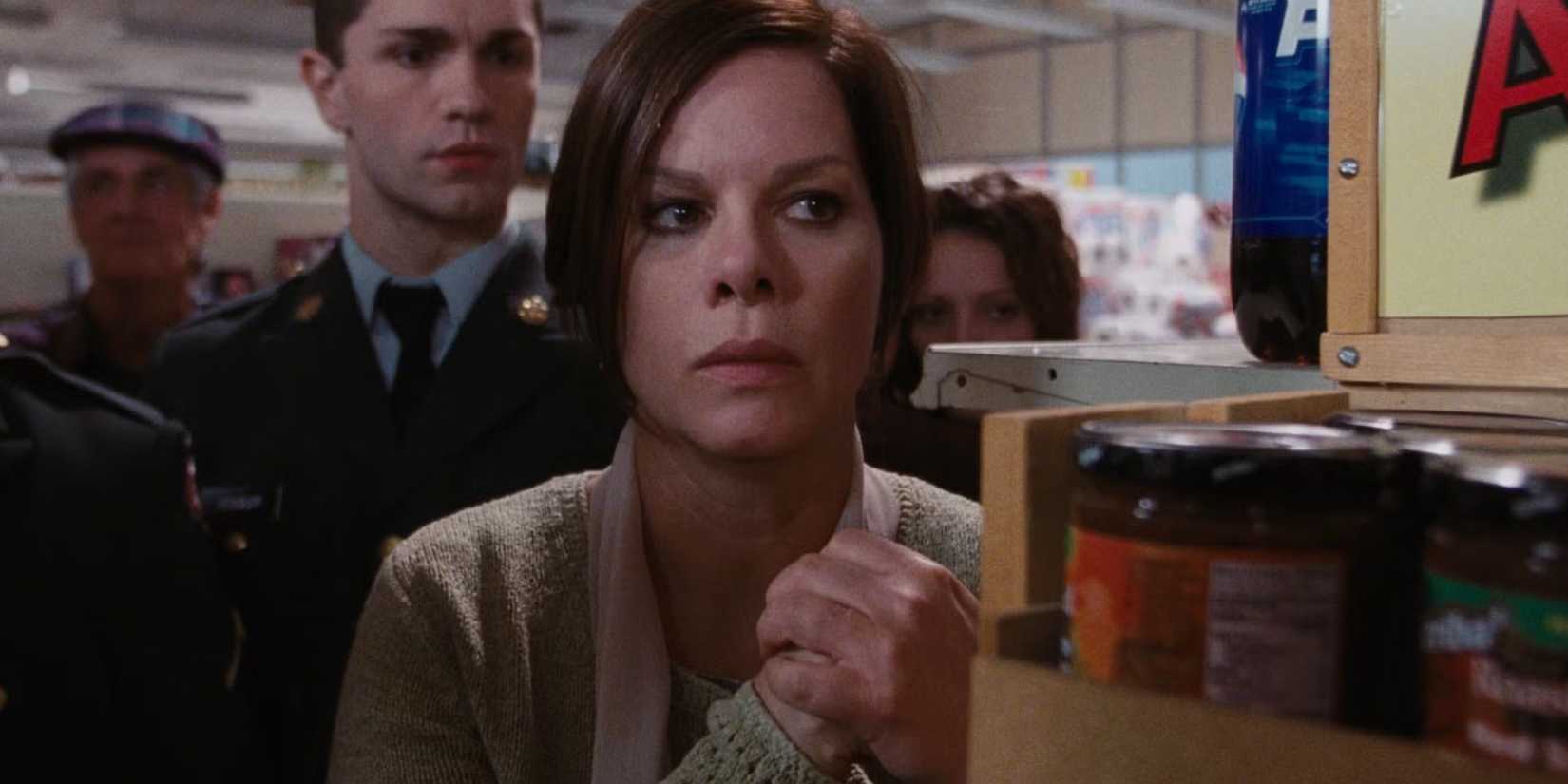 Marcia Gay Harden as Mrs. Carmody, standing behind a shelf looking suspicious in The Mist.