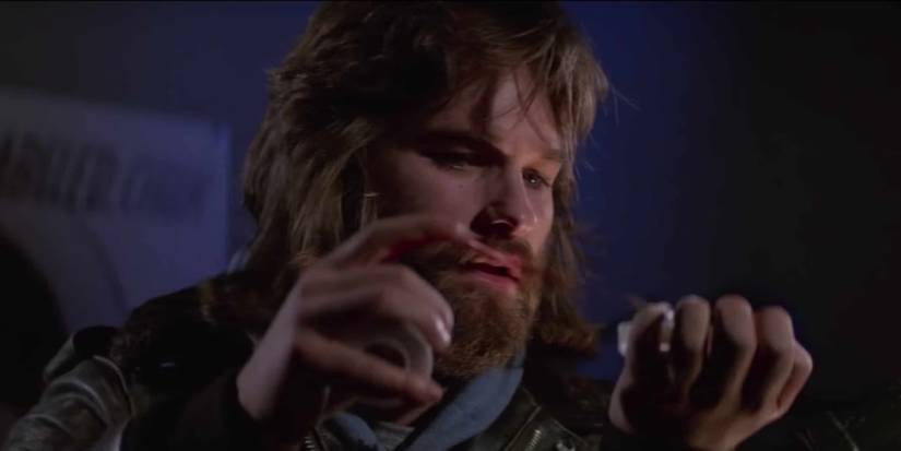 MacReady looking at something in his hands in The Thing