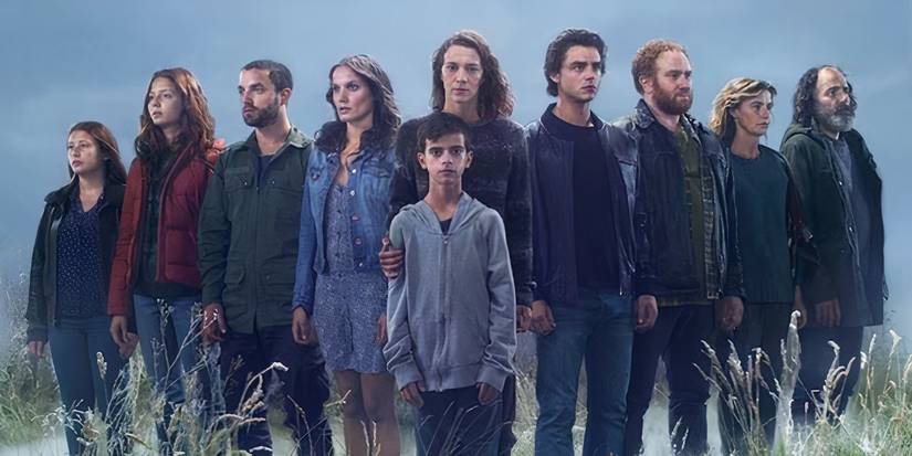 The cast of the Returned standing in a field looking in various directions.