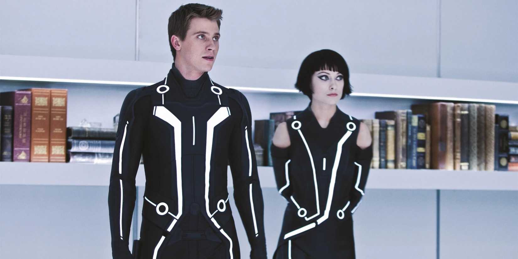 Garrett Hedlund and Olivia Wilde stand in front of a bookshelf in Tron: Legacy 