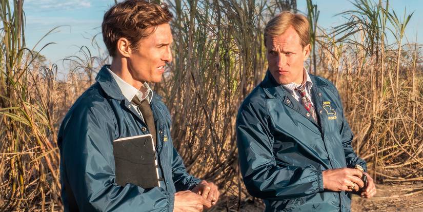 Matthew McConaughey and Woody Harrelson stand together by bushes in True Detective.
