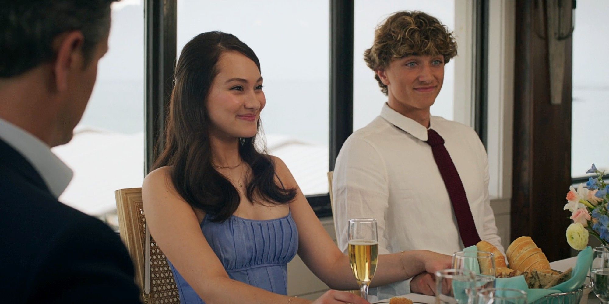 Belly Conklin and Jeremiah Fisher sitting next to each other and smiling at lunch in 'The Summer I Turned Pretty' Season 3.